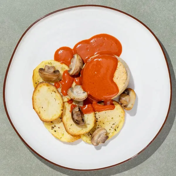 Pastel de merluza, salsa de piquillos y sidra, patatas y champiñones